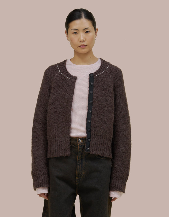 Easy fitting Eckhaus Latta bomber shape jacket in a twisted alpaca/wool boucle yarn. Features an invisible hand sewn metal snap closure and grosgran placket at front. Jacket is linked together with a contrast yarn.
