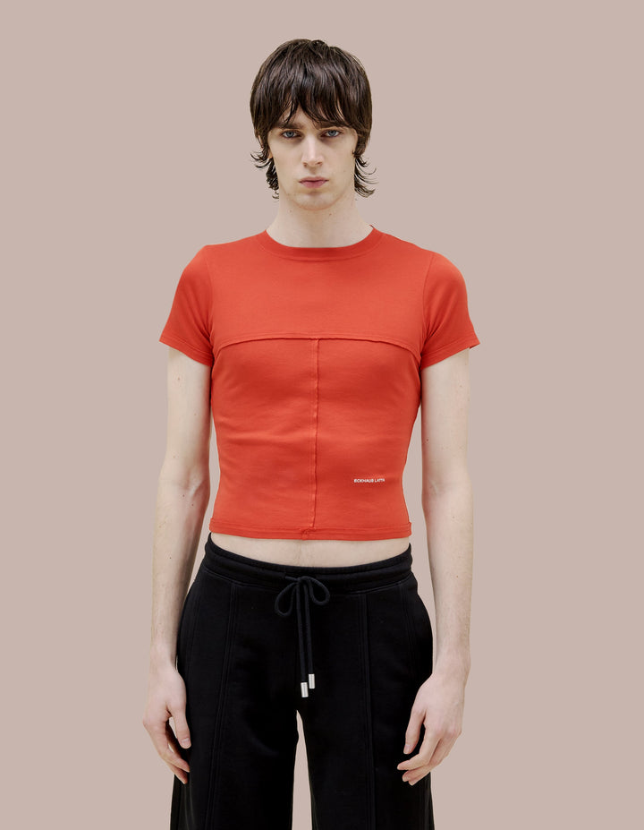Our classic lapped Eckhaus Lata baby tee in a 1x1 cotton baby rib. Fitted, slightly cropped. Topstitched raw edged seams create form-flattering vertical and horizontal lines across the body. Solid red garment dye finished with an off-white "Eckhaus Latta" logo on the abdomen.