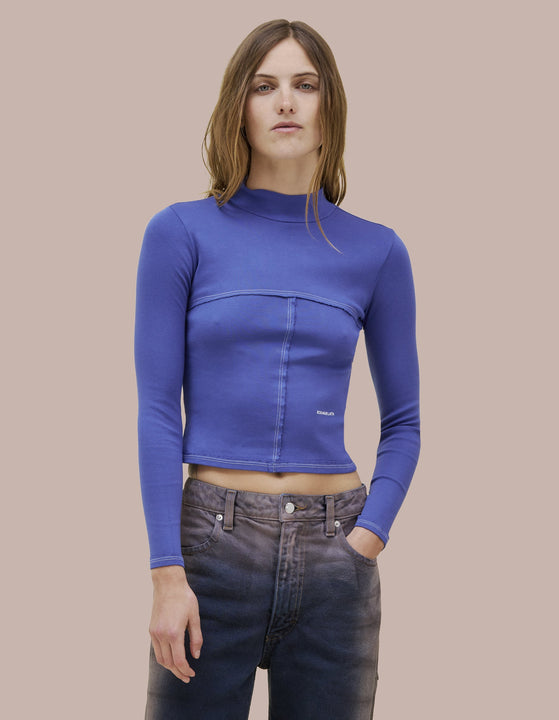 Our classic Eckhaus Latta lapped baby turtleneck in a 1x1 cotton baby rib. Fitted, slightly cropped. Topstitched raw edged seams create form-flattering vertical and horizontal lines across the body. Marine blue farment dye with pale pink contrast. Finished with pale pink "Eckhaus Latta" Logo on abdomen. 