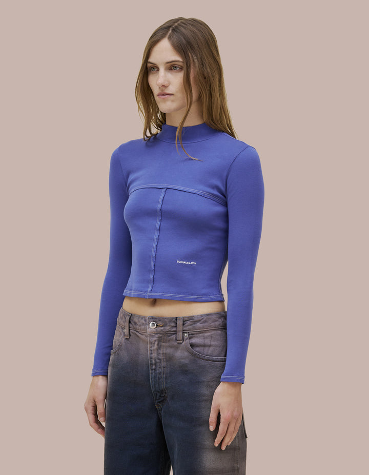 Our classic Eckhaus Latta lapped baby turtleneck in a 1x1 cotton baby rib. Fitted, slightly cropped. Topstitched raw edged seams create form-flattering vertical and horizontal lines across the body. Marine blue farment dye with pale pink contrast. Finished with pale pink "Eckhaus Latta" Logo on abdomen. 