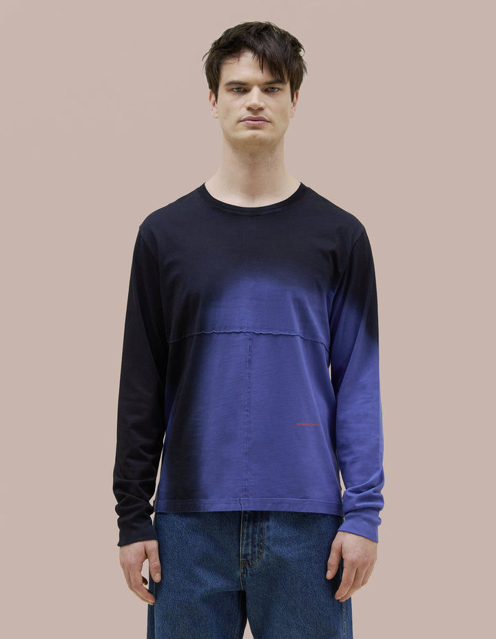 Our classic Eckhaus Latta relaxed-fit lapped long sleeve in a pima cotton jersey. The top is broken up into multiple lapped pieces with the raw edged seams highlighted by topstitching. Vibrant blue garment dyed with black spray detailing and a red "Eckhaus Latta" logo at abdomen.