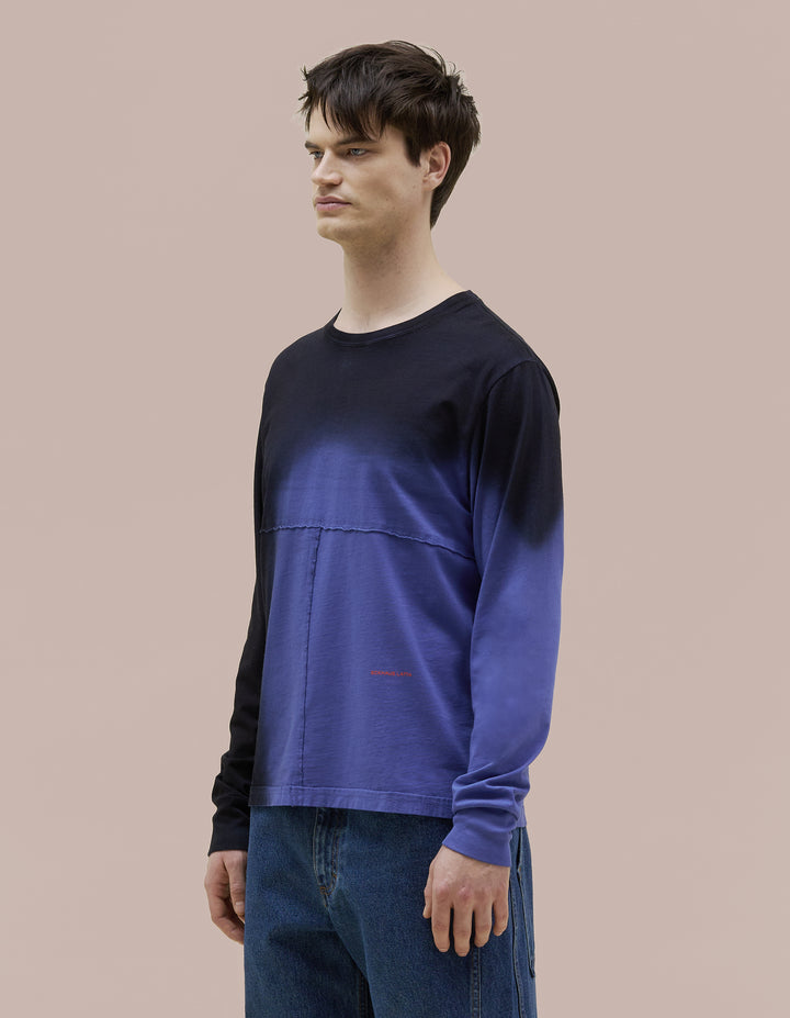 Our classic Eckhaus Latta relaxed-fit lapped long sleeve in a pima cotton jersey. The top is broken up into multiple lapped pieces with the raw edged seams highlighted by topstitching. Vibrant blue garment dyed with black spray detailing and a red "Eckhaus Latta" logo at abdomen.