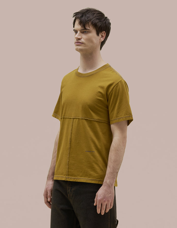Our classic Eckhaus Latta  relaxed fit tee in Pima cotton jersey with lapped raw-edged seams. Garment dyed in solid olive green with ultramarine blue contrast topstitching. Finished with an ultramarine blue "Eckhaus Latta" logo on the abdomen.