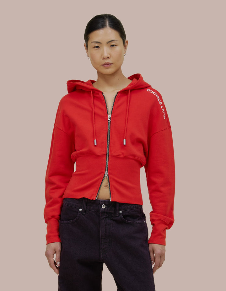 Our classic Eckhaus Latta snatched hoodie style in a brushed French terry with a fitted ribbed hem band. Garment dyed in solid red, finished with a glossy off-white "Eckhaus Latta" logo on the shoulder.