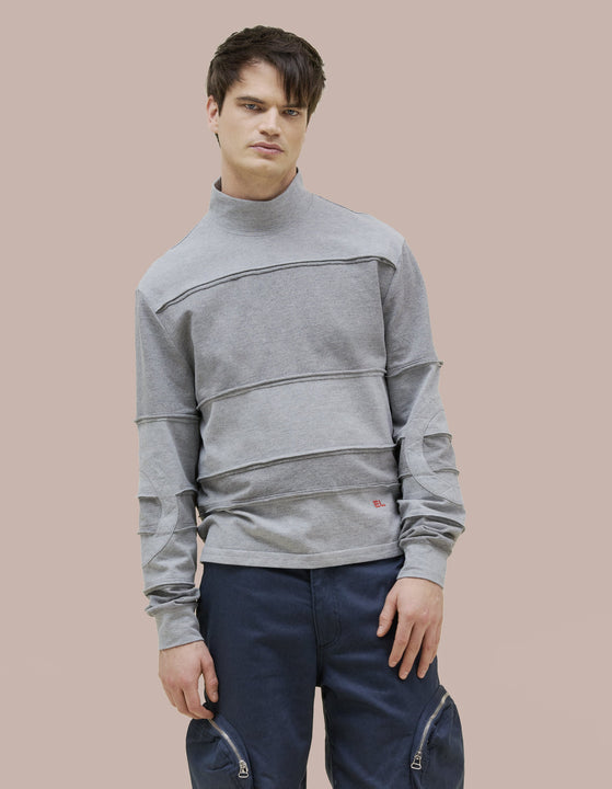A relaxed-fit Eckhaus Latta long sleeve turtleneck with a two way metal zipper along the center back. Stripes are assembled from individual strips, finished externally to echo our signature lapped seams. Red "EL" logo embroidery at the lower left abdomen.